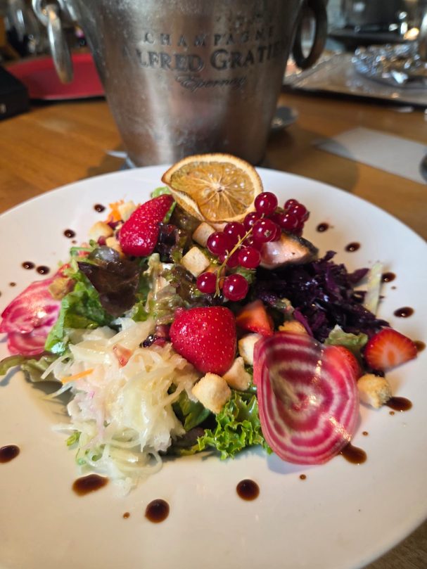 Bunte Salatplatte mit Beeren, Zitrusfrüchten und Kräutern, dekoriert mit Balsamico.